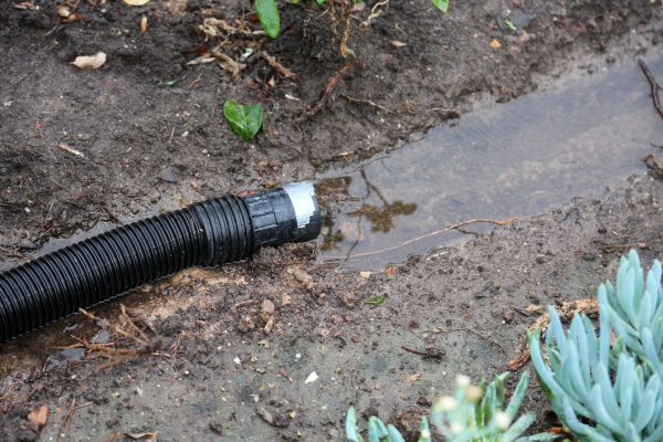 A,Black,Plastic,Hose,Attached,To,A,House,Rain,Gutter